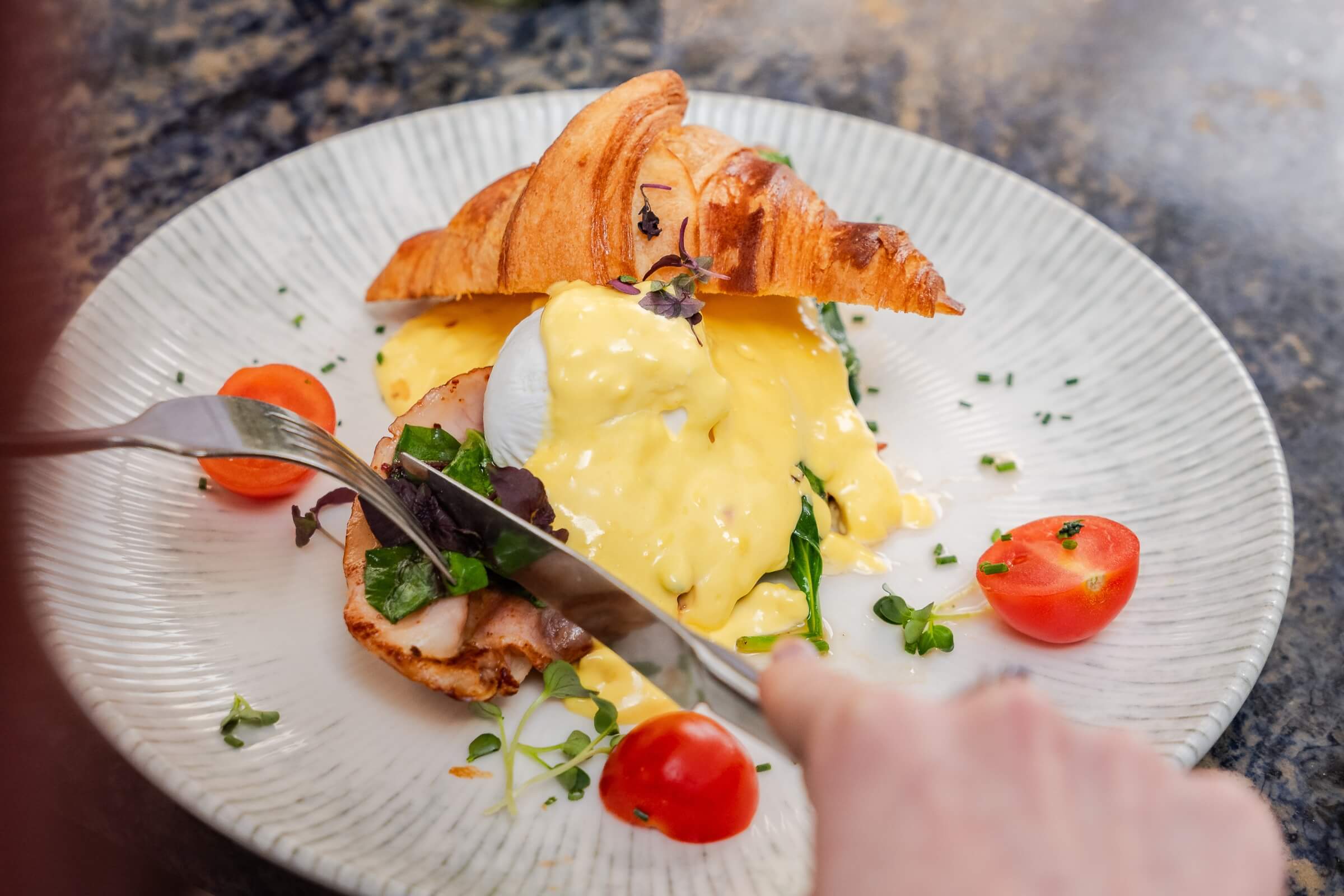 Eggs Benedict Royale auf Croissant mit Tomaten im Detail